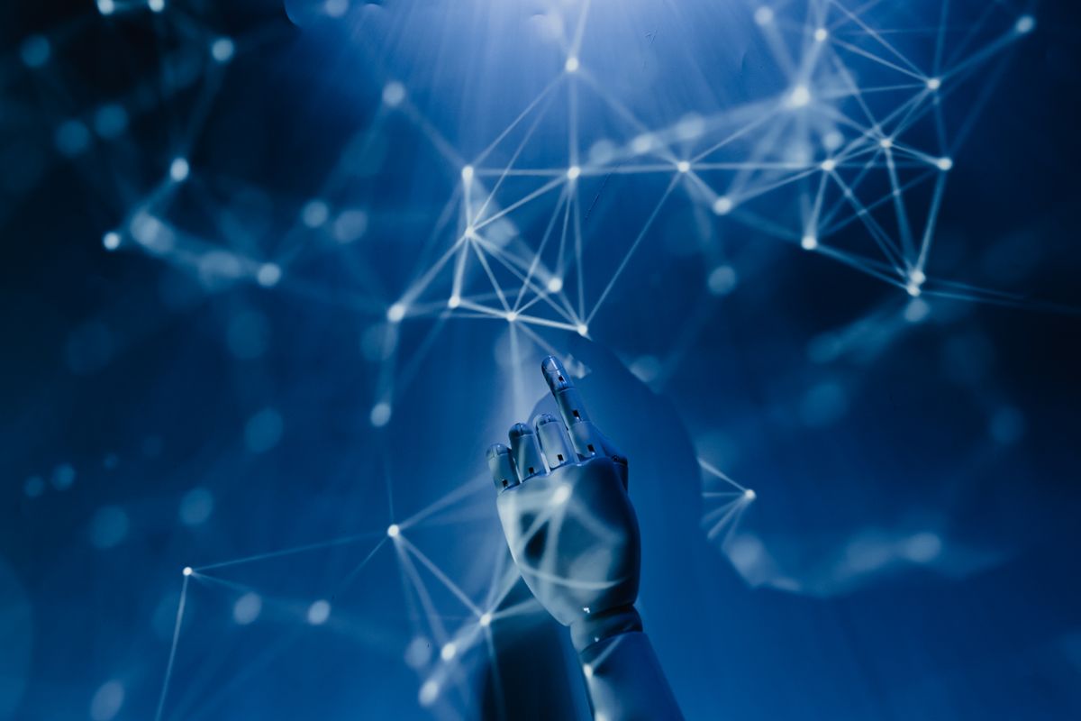 A white robotic hand reaching toward a glowing blue network of connected nodes representing a neural network